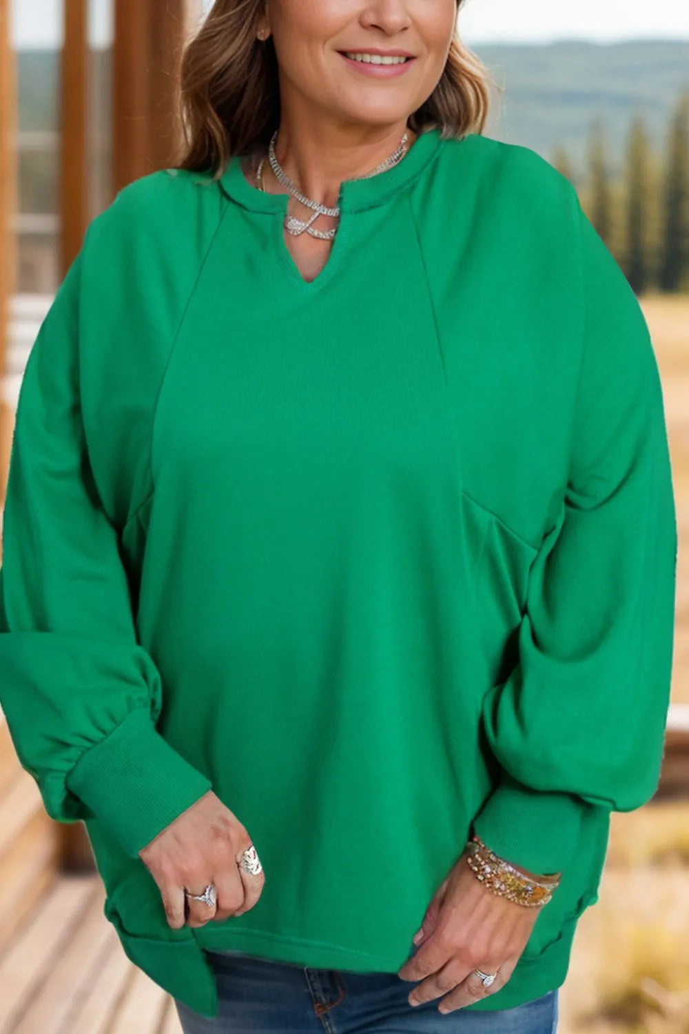Person wearing a green sweater with a blurred natural background