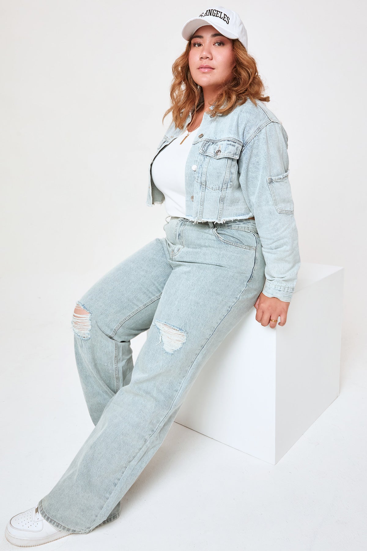 Person wearing a light blue denim outfit with a white background