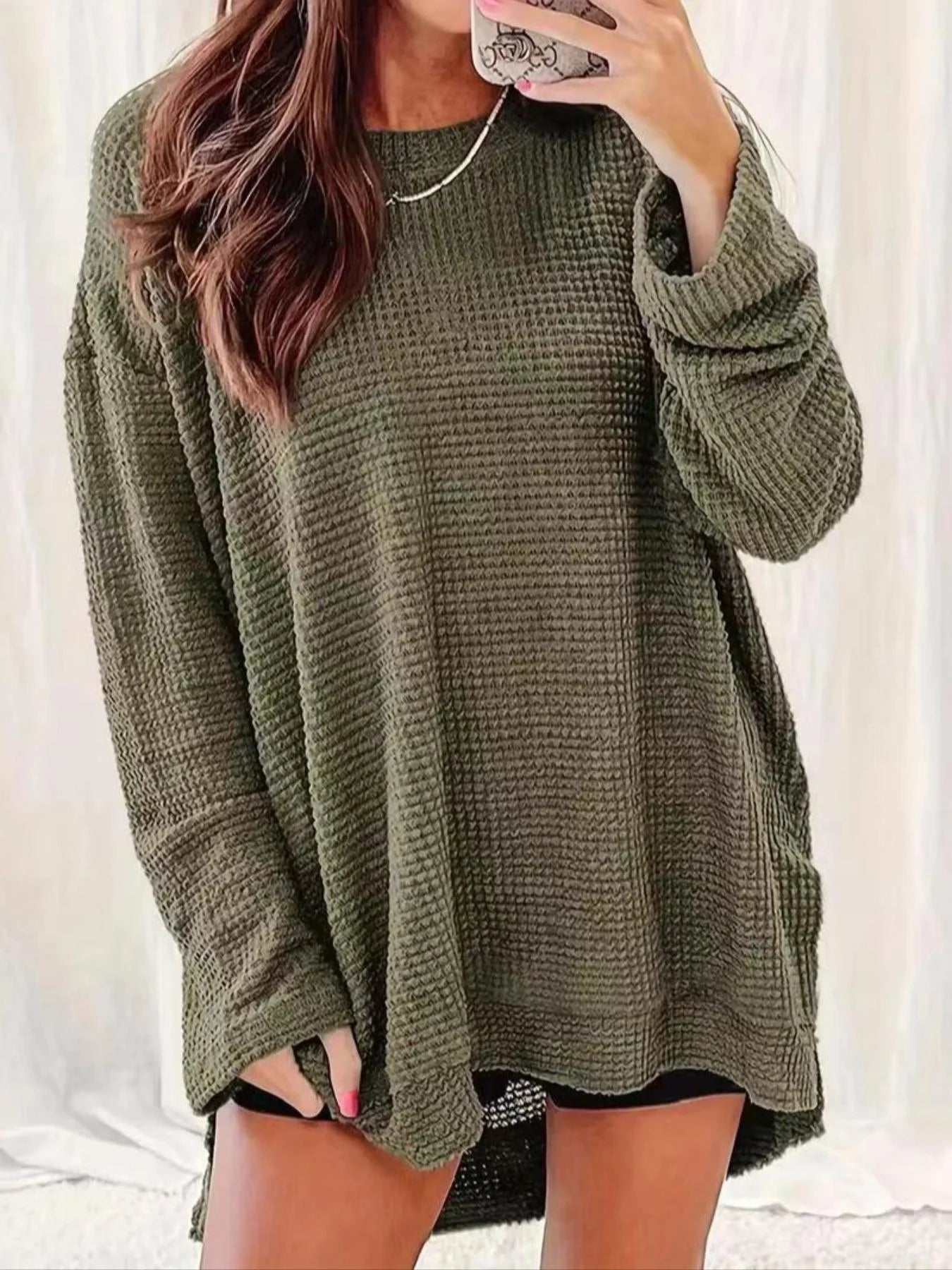 Person wearing a green oversized sweater against a white background