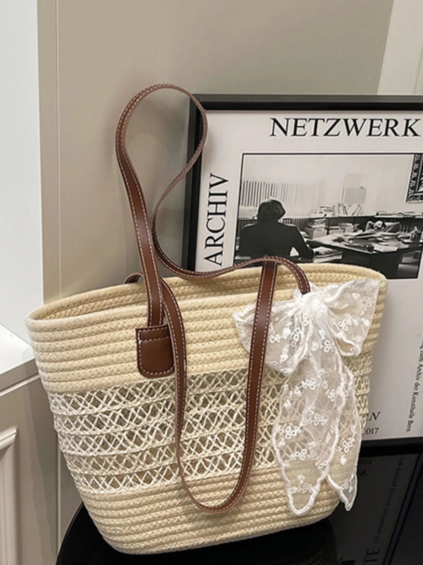 Woven handbag with lace detail in front of a framed picture