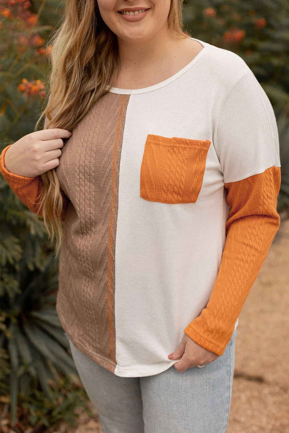 Person wearing a long-sleeve shirt with orange, white, and brown color block design.
