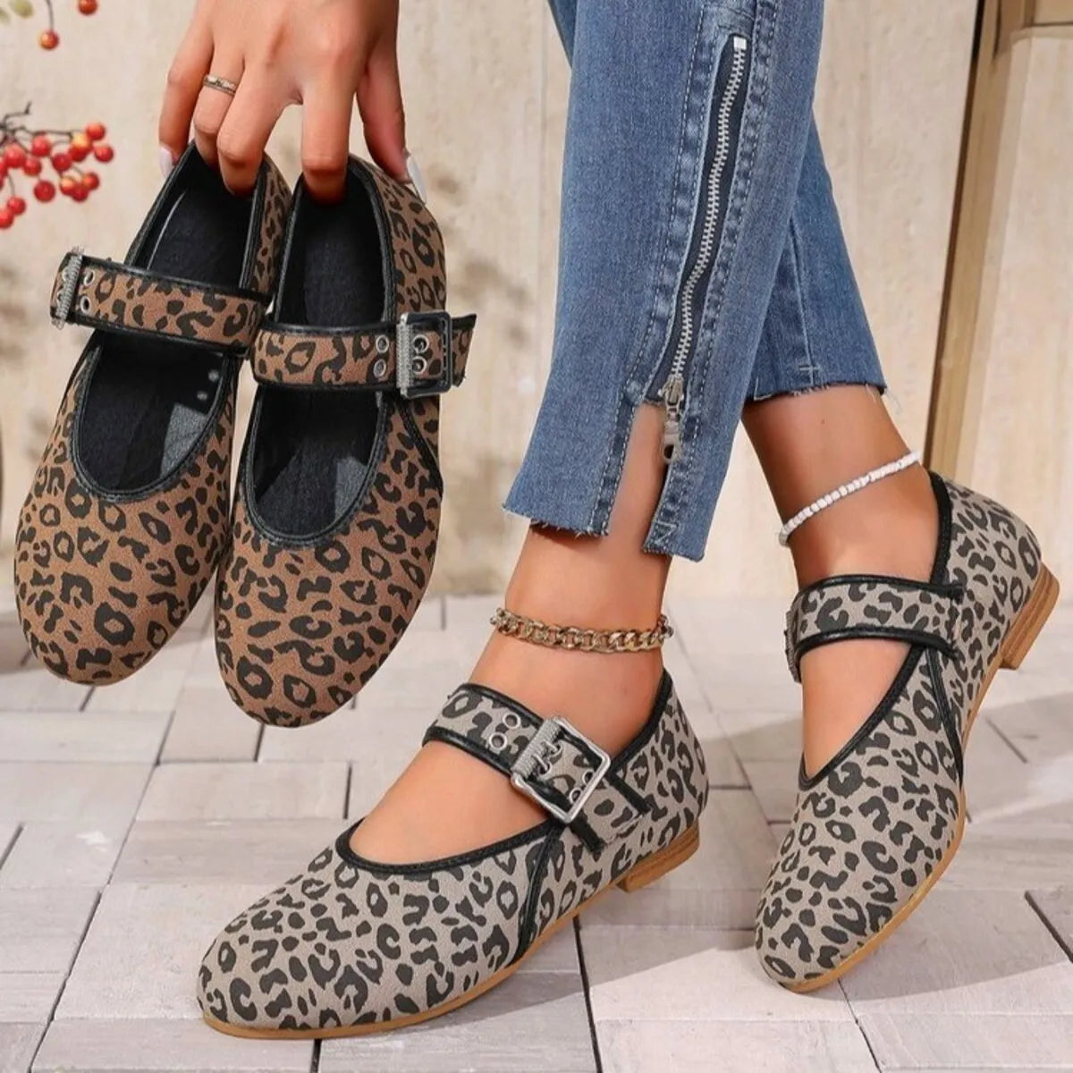 Leopard print shoes being held by a person wearing jeans.
