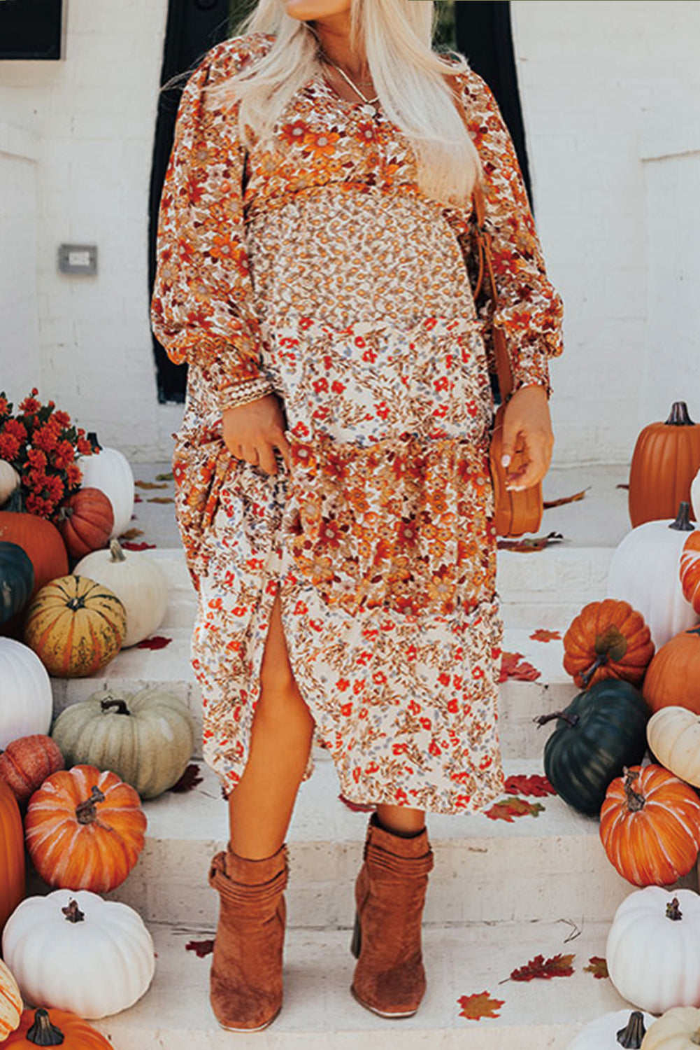 Woman in a floral dress with pumpkins and autumn decorations