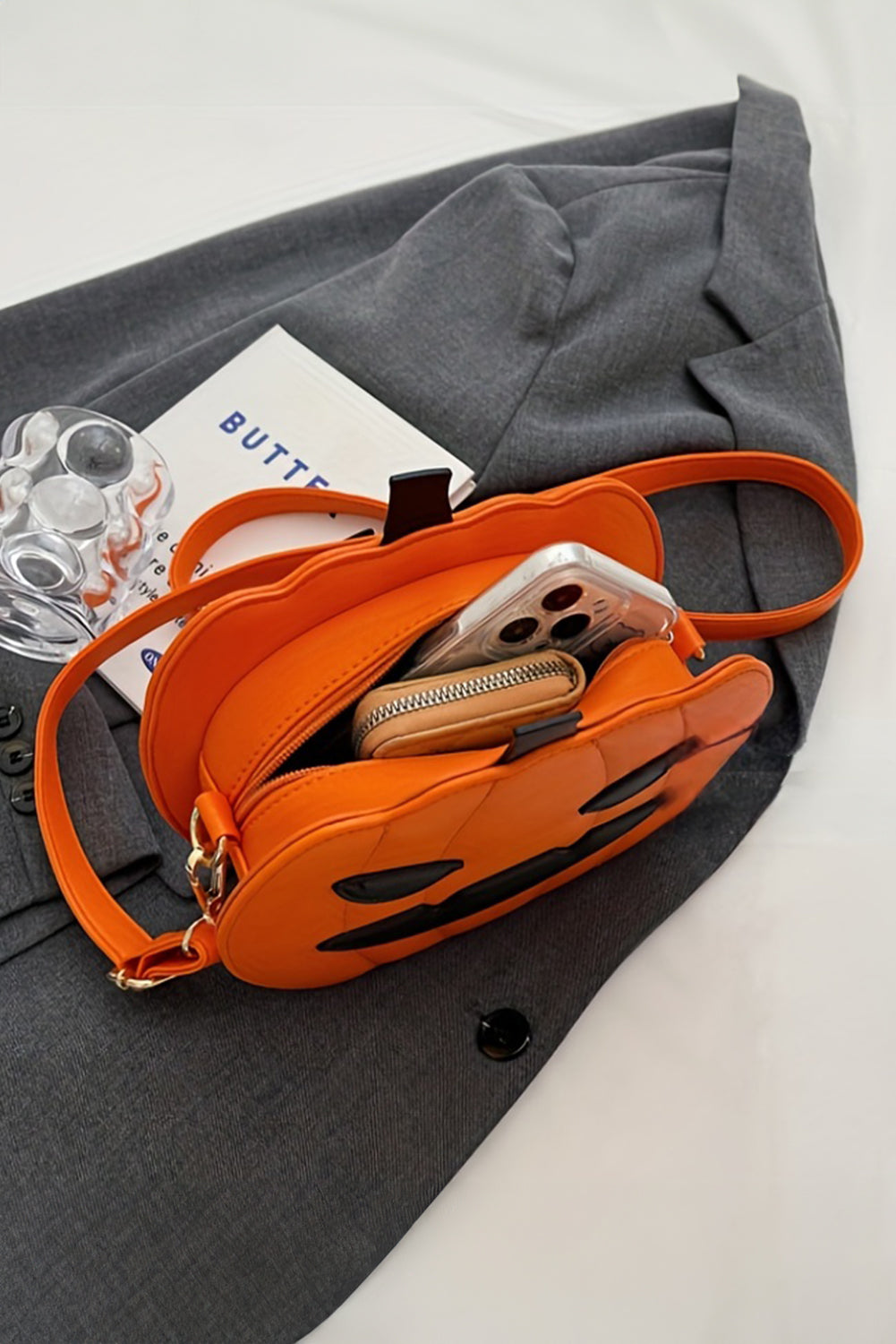Orange handbag with phone case on a gray fabric background