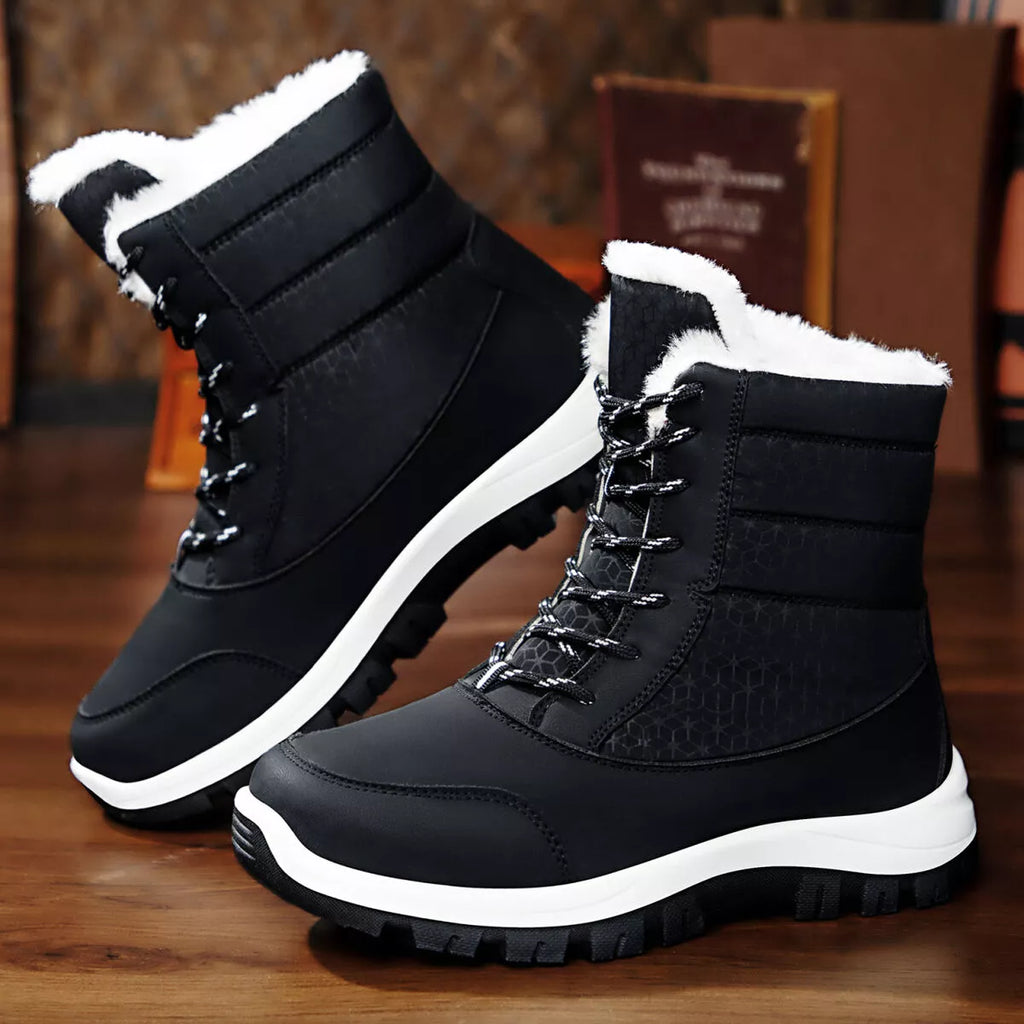 Black winter boots with white soles on a wooden floor