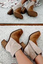 Pair of brown and beige suede ankle boots on a textured surface