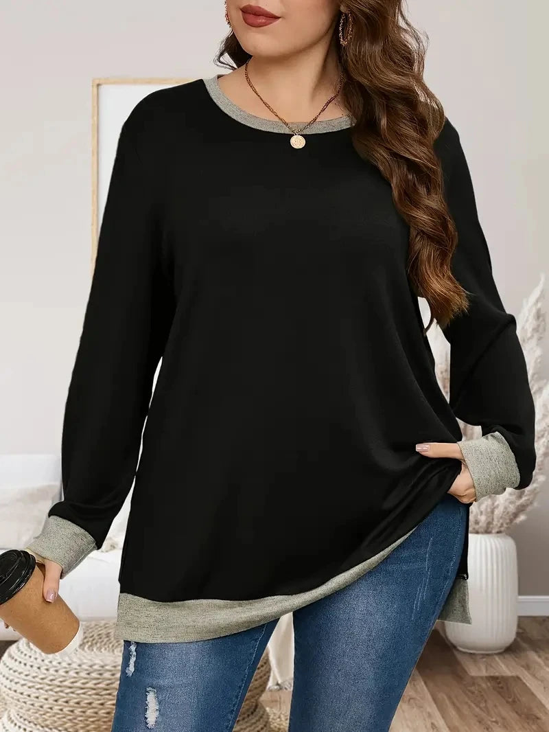 Woman wearing a black long-sleeve top with gray trim in a home setting.
