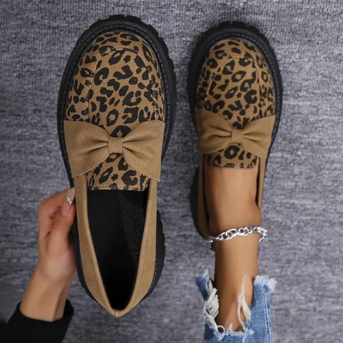 Leopard print loafers with a bow on a gray background